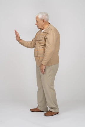 Vista lateral de un anciano con ropa informal que muestra un gesto de parada