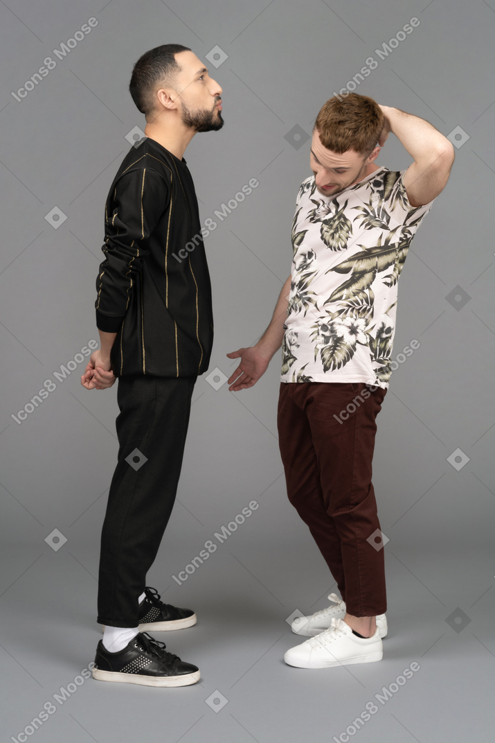 Two young men standing in front of each other looking puzzled