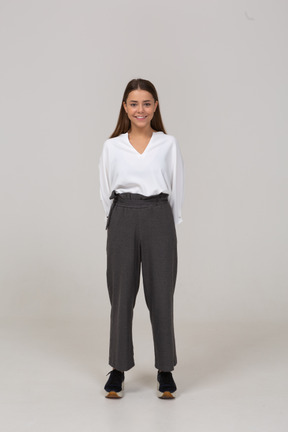 Front view of a smiling young lady in office clothing holding hands behind