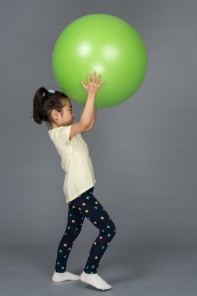 Niña sosteniendo un fitball verde