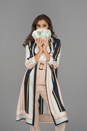 Allegra donna mediorientale che si copre il viso con un ventaglio fatto di banconote