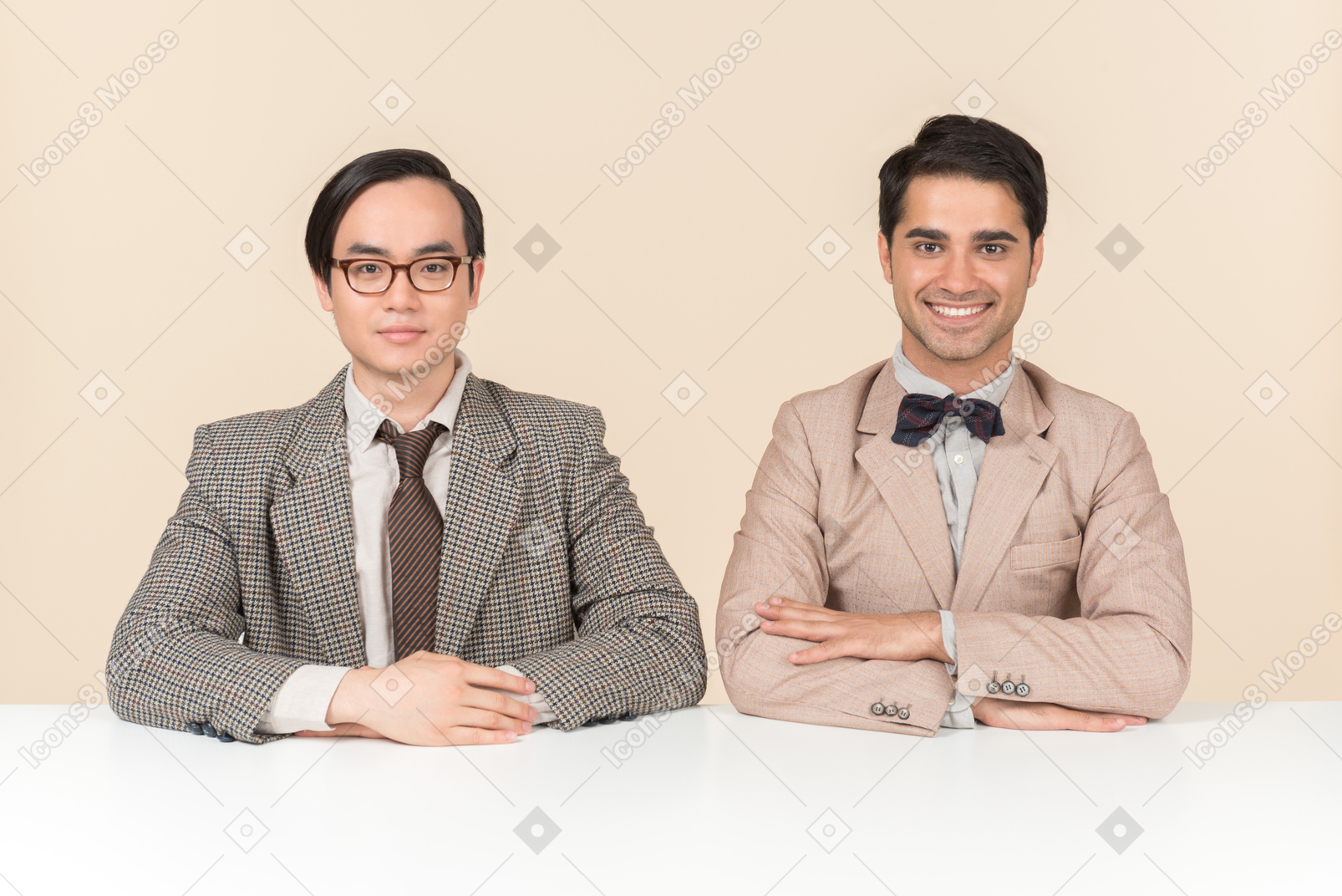 Dois jovens nerds sentado à mesa com os braços cruzados