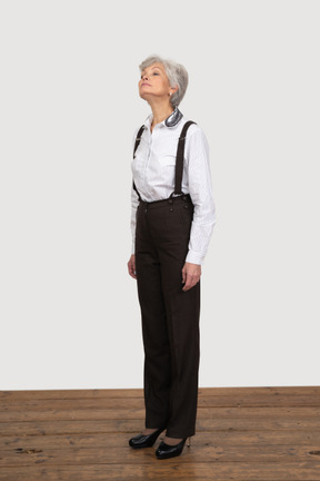 Vista di tre quarti di una donna anziana fiduciosa vestita in abiti da ufficio