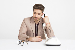 Jovem bonito segurando o receptor do telefone perto da orelha