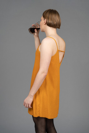 음료를 마시는 오렌지 드레스를 입은 젊은 사람의 뒷모습