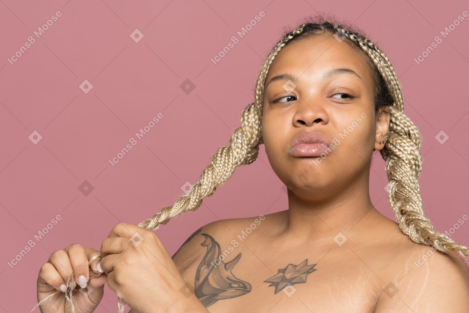 Frown tattooed african-american woman braiding her blond hair