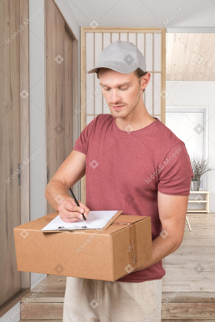 A man holding a box and writing on a piece of paper
