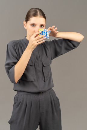 Front view of young woman in a jumpsuit holding the rubik's cube