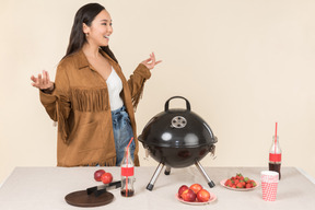 Young asian woman standing near closed grill on the table