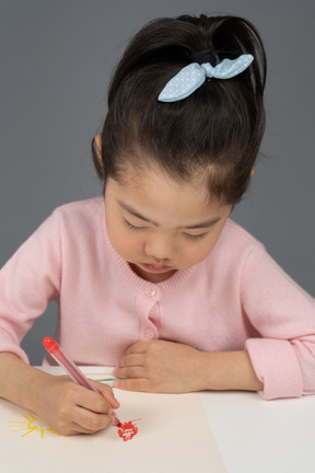 Serious little girl sitting still at her desk