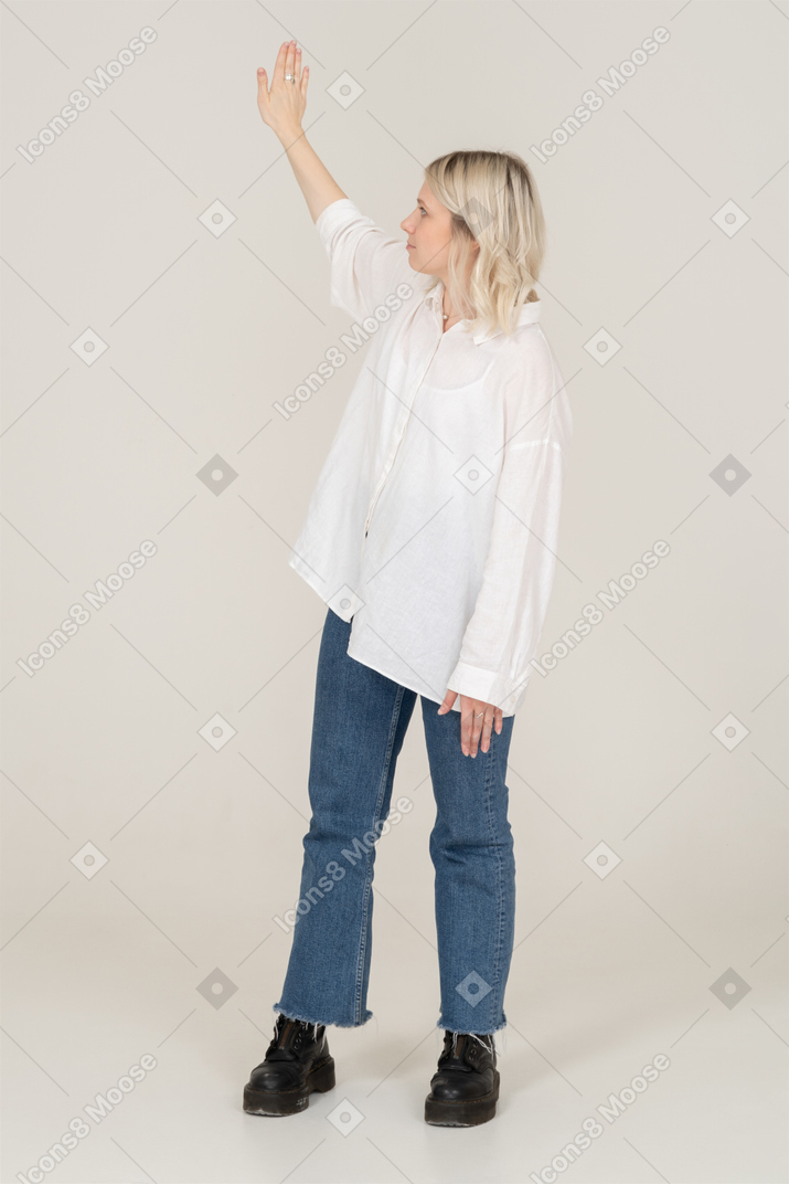 Vista frontal de uma jovem loira se virando e levantando a mão