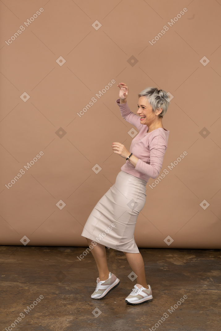 一个穿着休闲服跳舞的快乐女人的侧视图