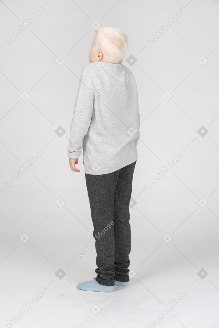 Vista traseira de três quartos de um menino encolhendo os ombros