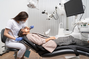 Longitud total de una dentista examinando a su paciente acostada en un gabinete de hospital