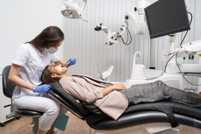 Full-length of a female dentist examining her female patient lying in a hospital cabinet