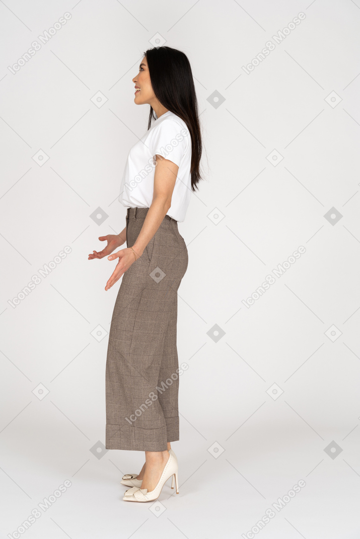Vista lateral de uma jovem sorridente de calça e camiseta