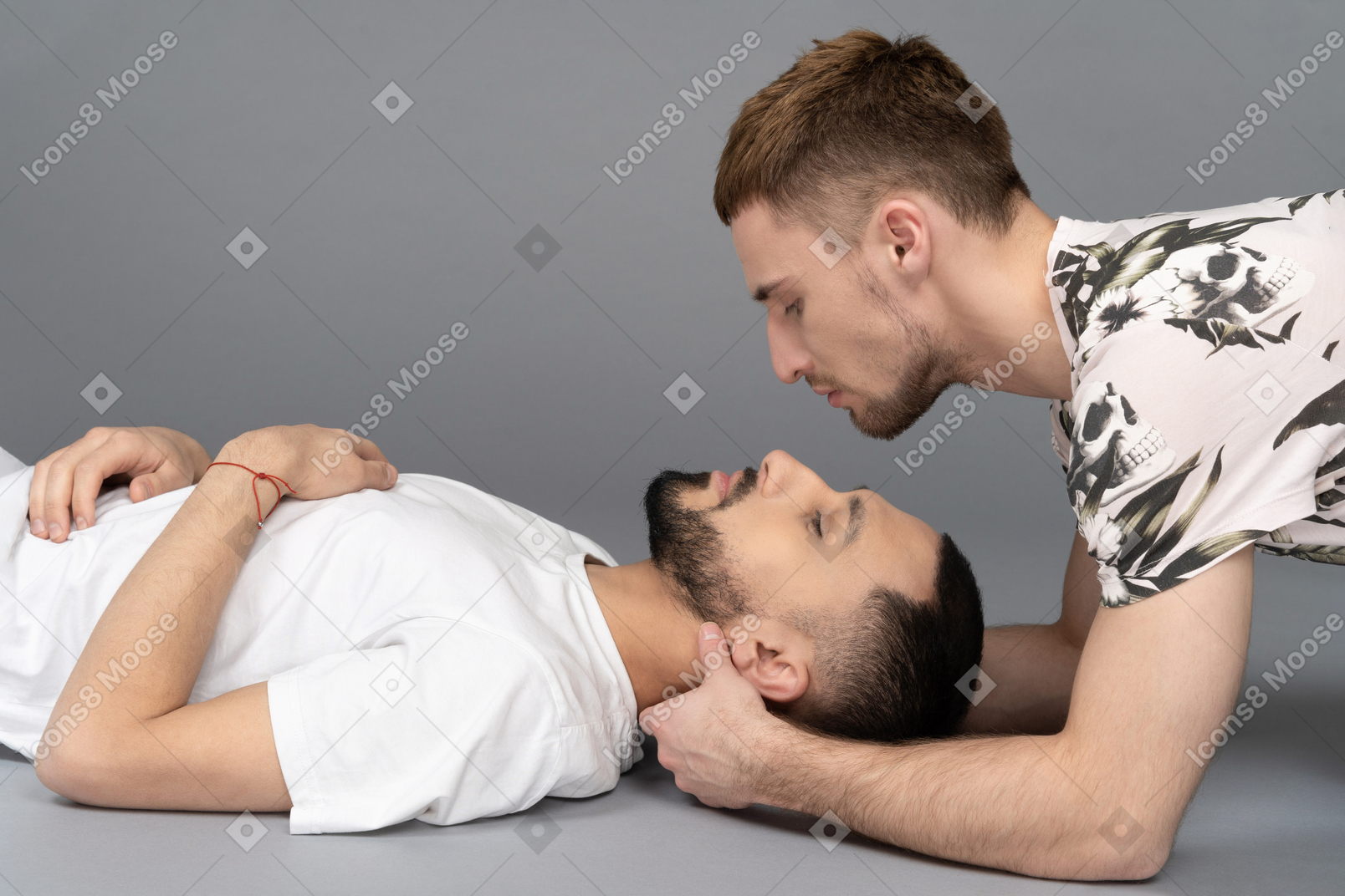 Two young caucasian men lying on the floor one looming over another gently