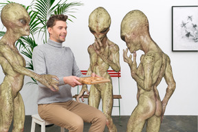 A man sitting on a chair next to a group of aliens