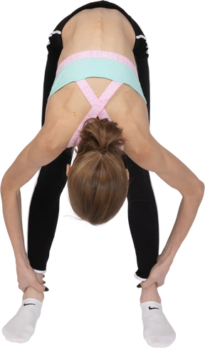 Front view of a teen girl in sportswear stretching while holding ankles