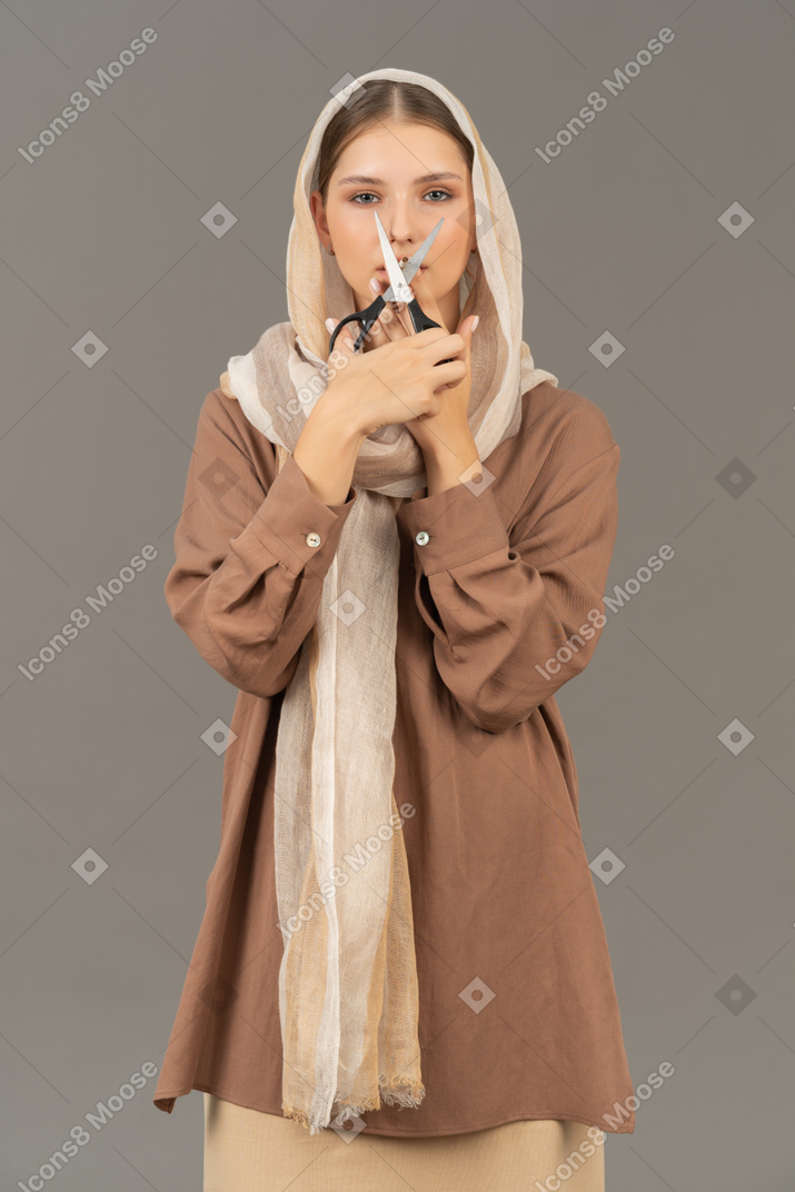 Woman in beige clothes cutting a cigarette with scissors