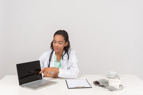 Confiante médico feminino mostrando algo em seu laptop