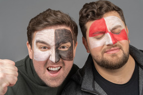 Front view of two male football fans with face art