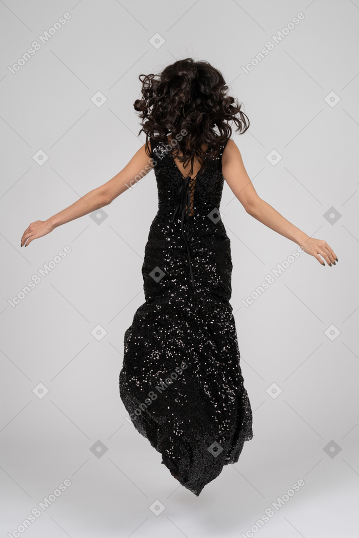 Hermosa mujer en saltos de vestido de noche negro