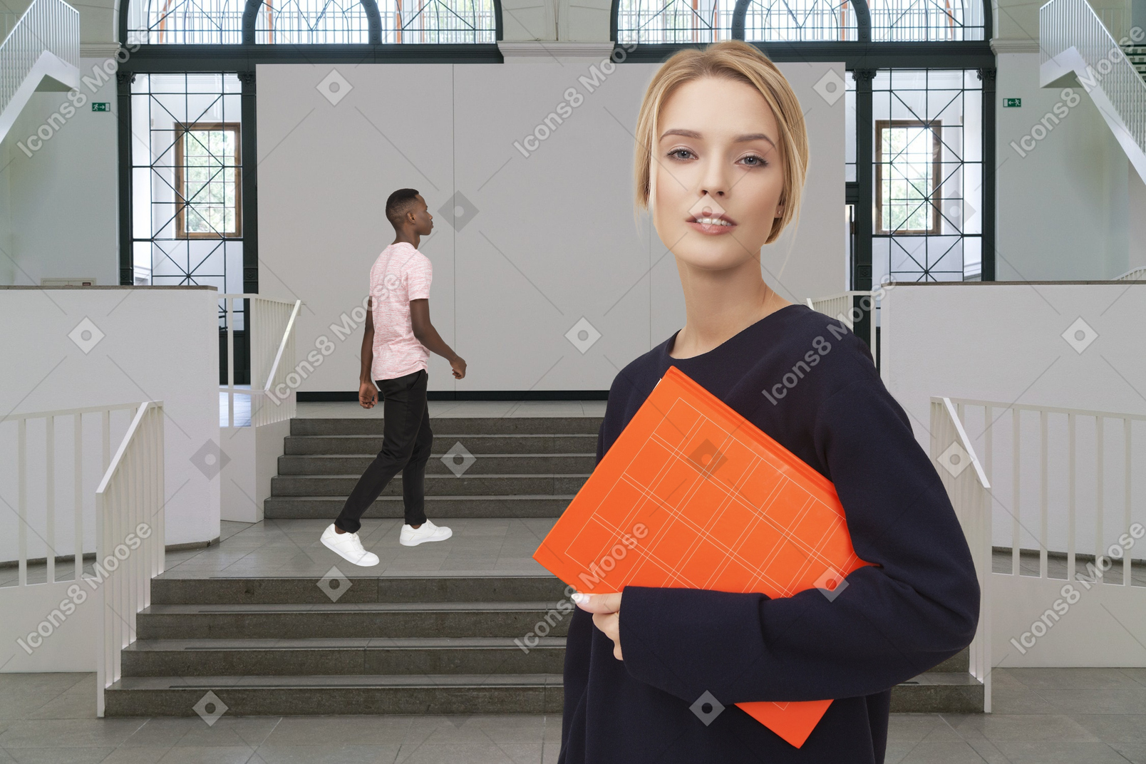 A woman holding an orange folder standing in front of a staircase