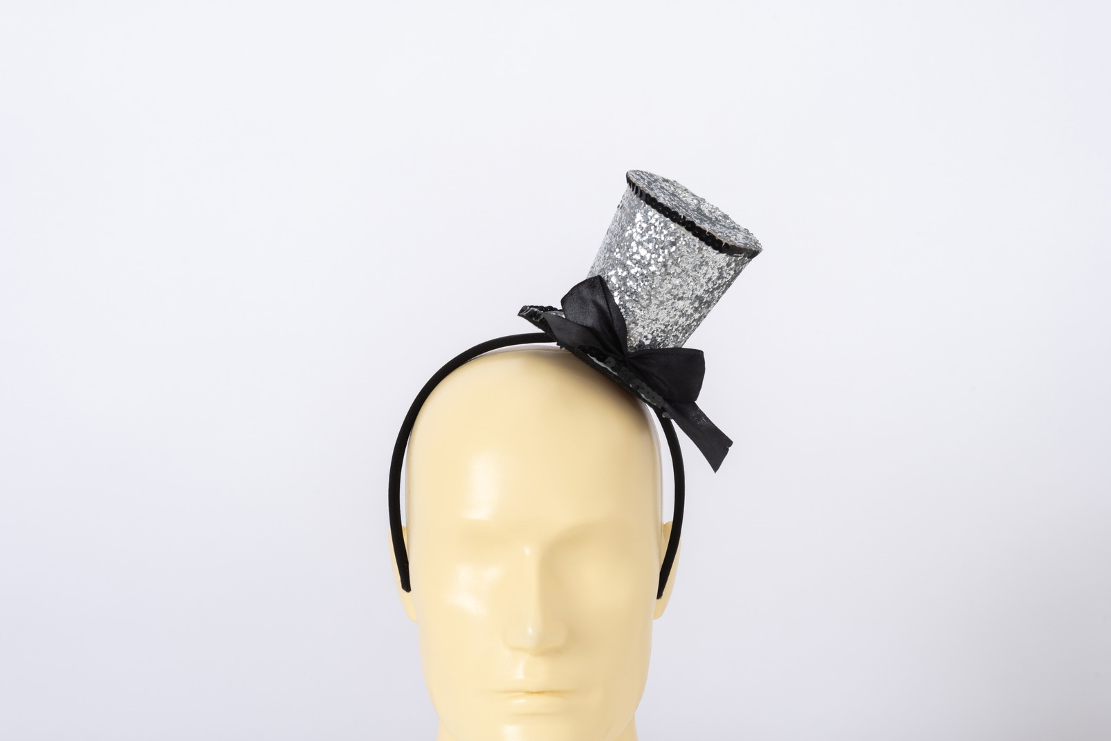 Small silver top hat with a bow on a mannequin head