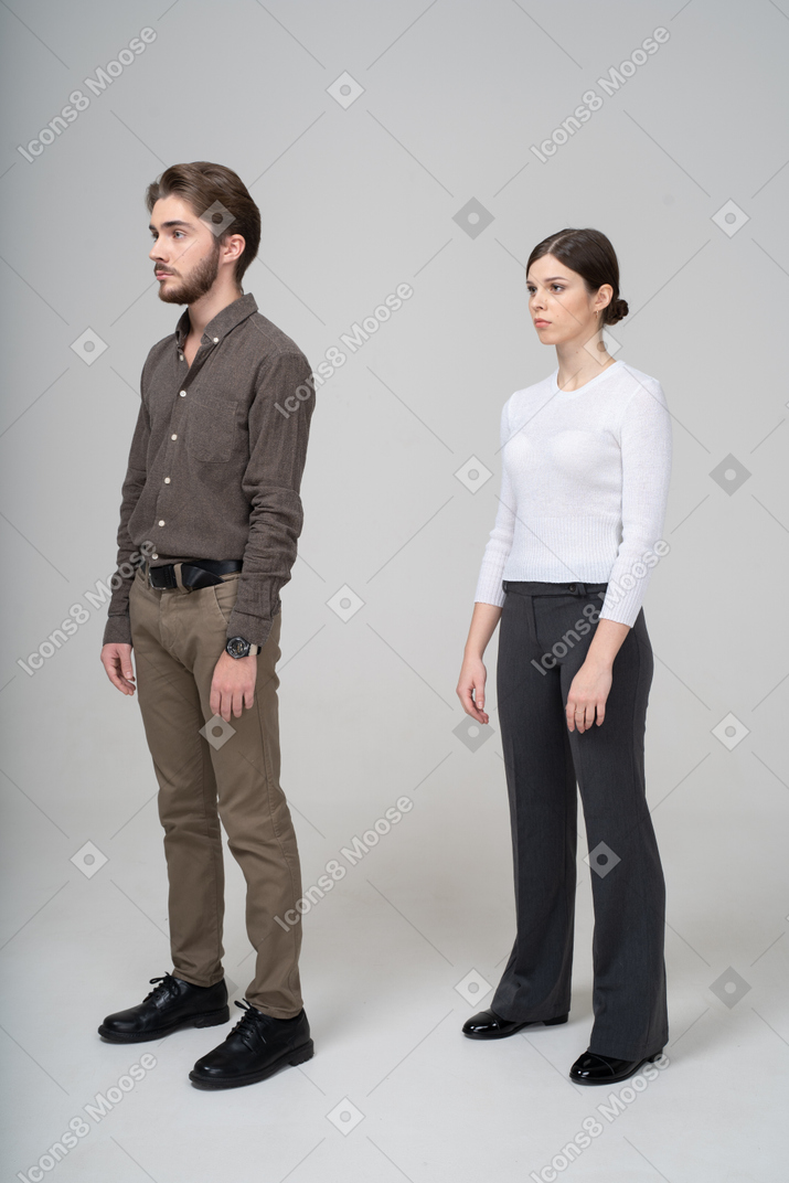 一对年轻夫妇在办公室服装站着不动的四分之三视图