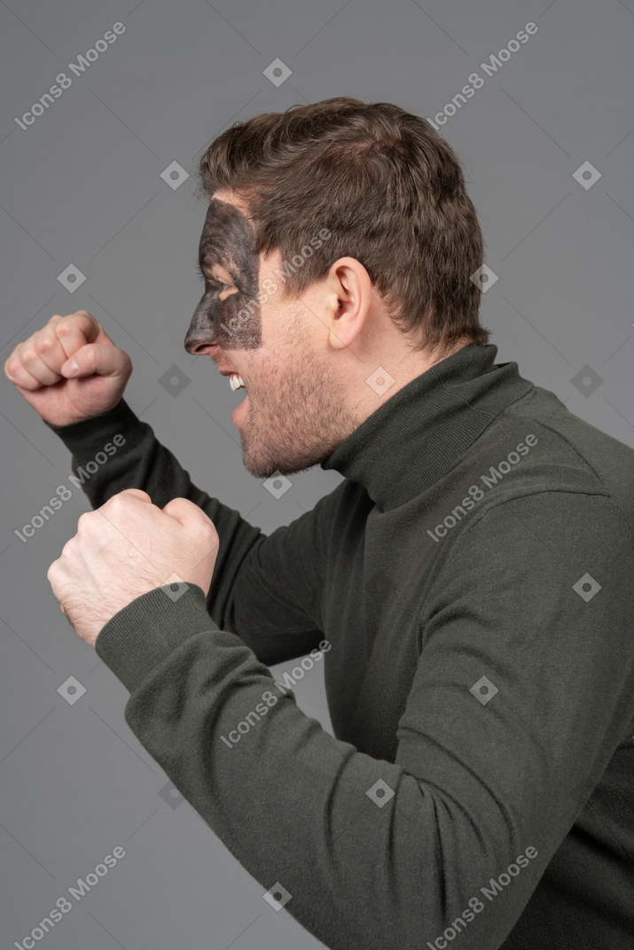 Side view of a screaming male football fan clenching fists