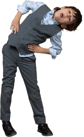 Vista frontal de un niño en traje posando con las manos en las caderas