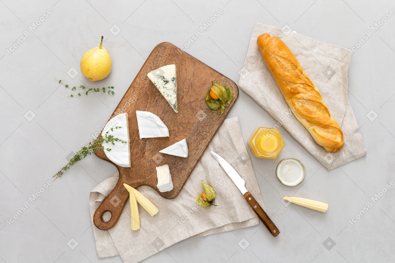 Tábua de cortar com alguma baguete e queijo, algumas pêras e mel