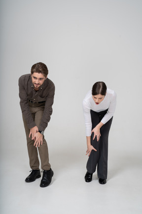 Vista frontal de um jovem casal com roupas de escritório tocando o joelho