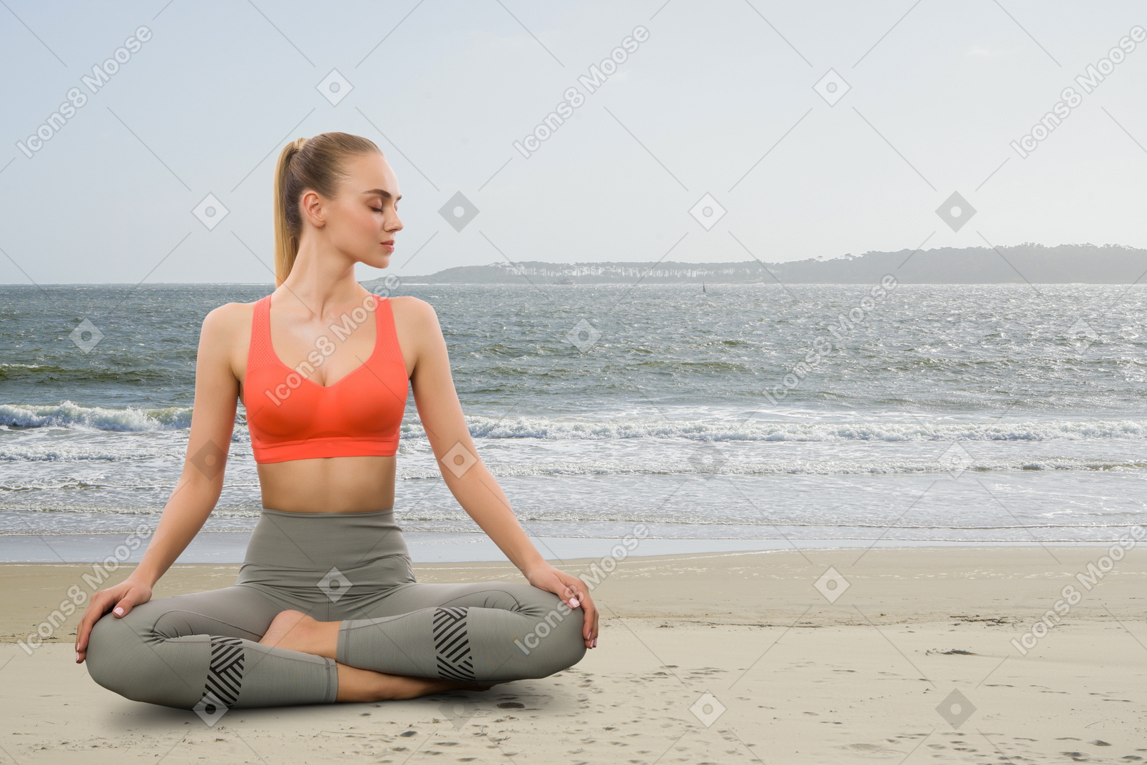 A woman sitting in a yoga position on the beach