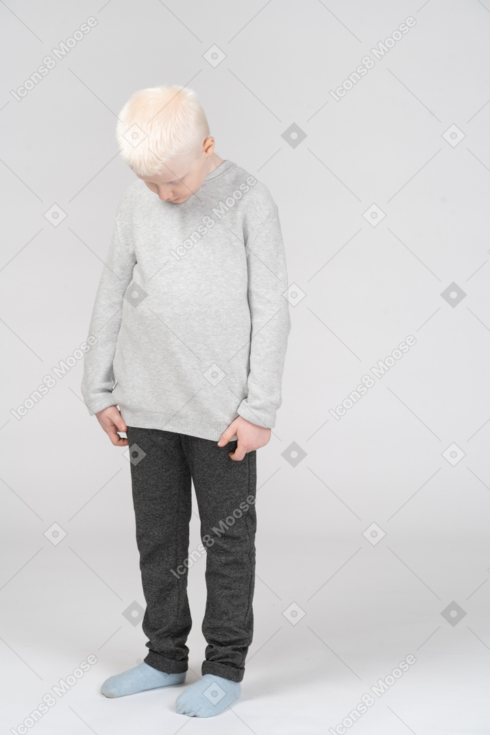 Front view of a kid blonde little boy looking down