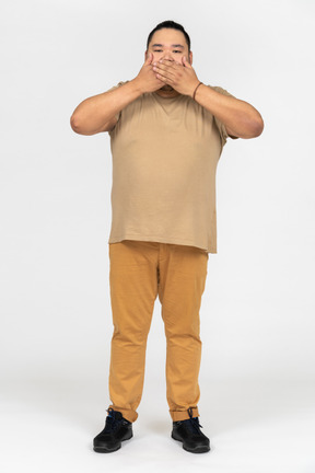 Plump asian man covering his eyes with both hands