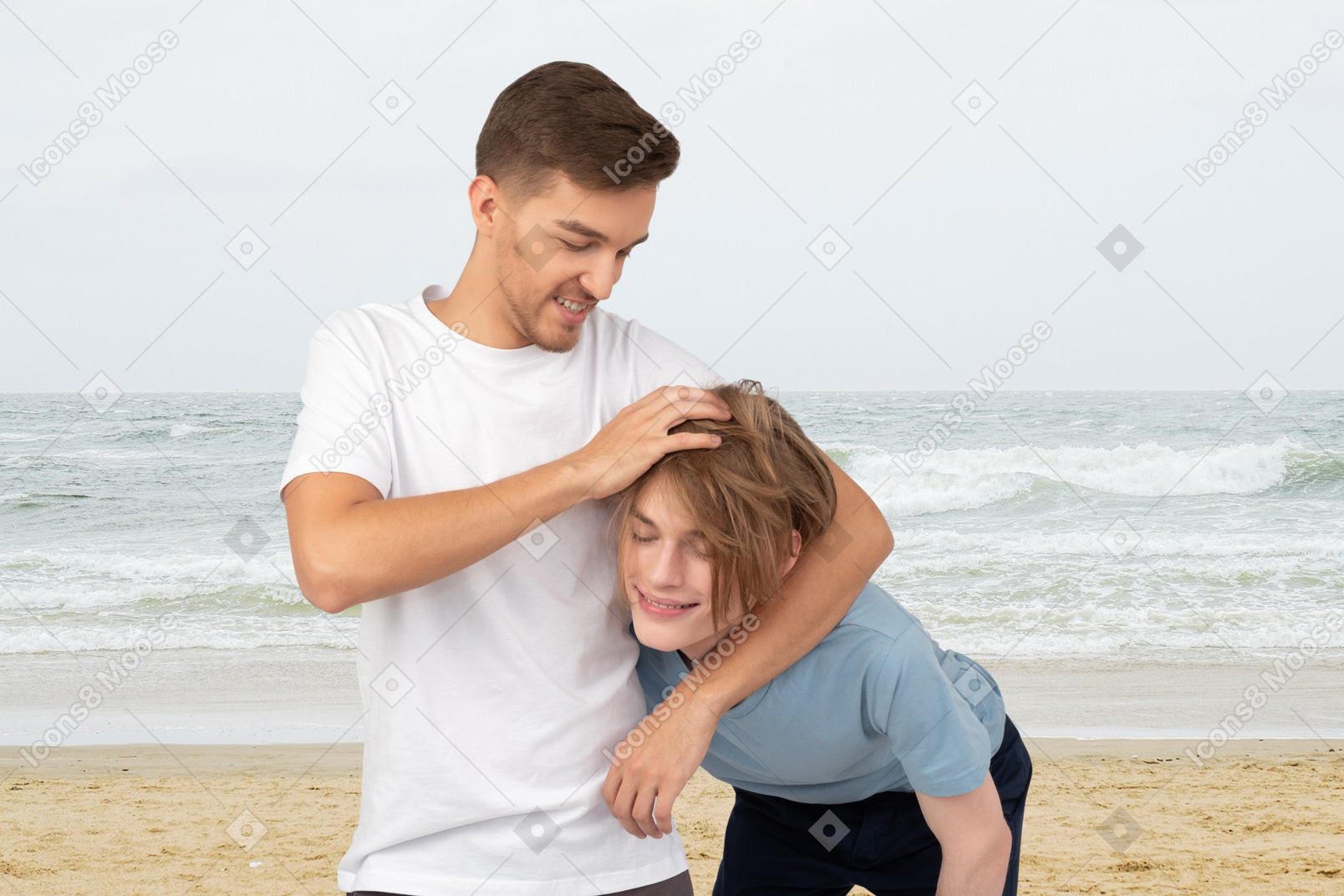A man messing up a woman's hair on the beach