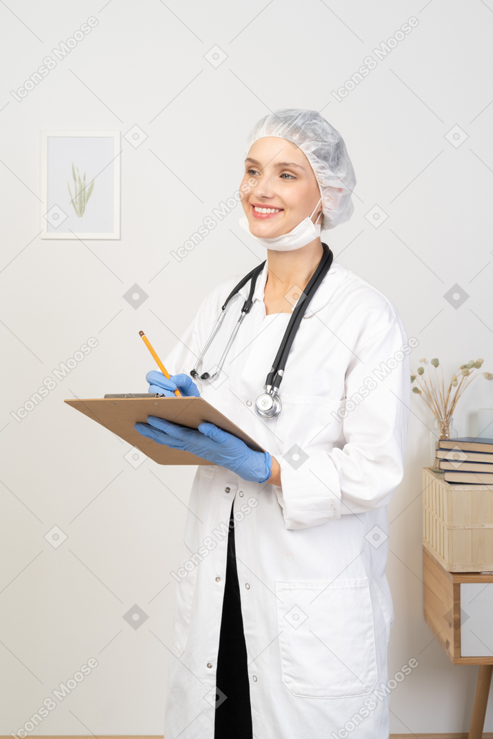 Vista de três quartos de uma jovem médica fazendo anotações em seu tablet