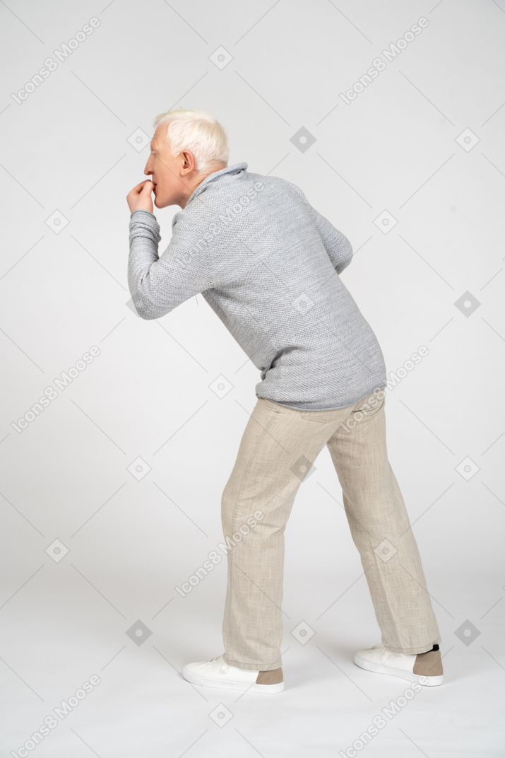 Side view of a man standing and biting nails