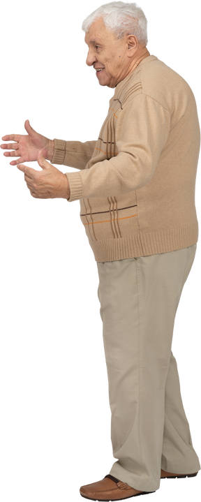 Side view of a happy old man in casual clothes standing with outstretched arms