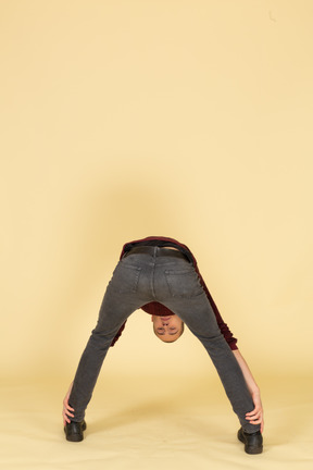 Back view of a young man in red pullover bending down low