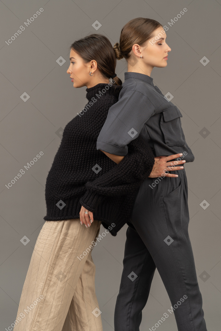 Two women standing back to back