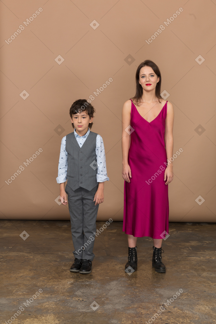 웃는 소년과 함께 서 있는 빨간 드레스를 입은 여자