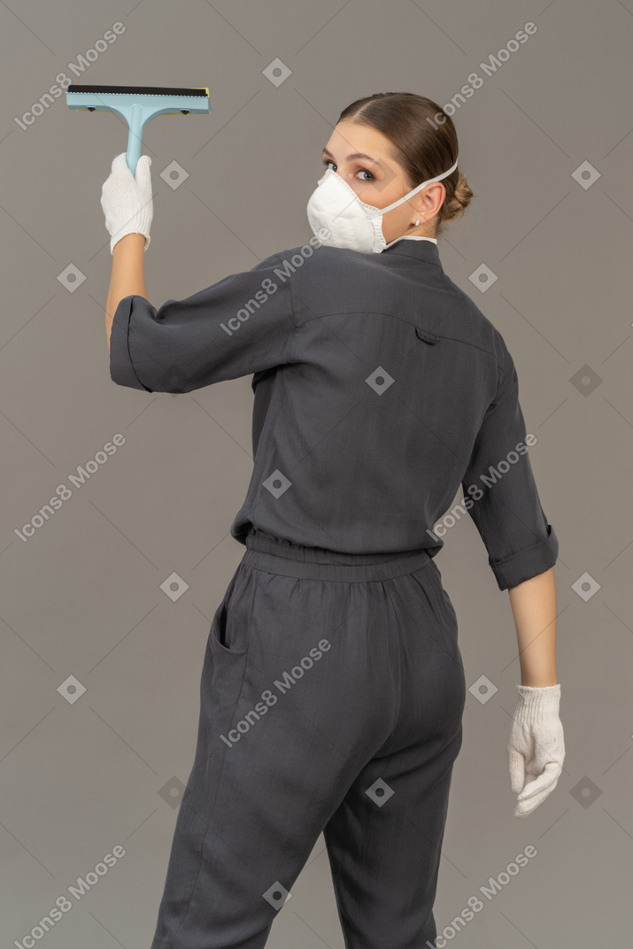 Rear view of a woman looking over shoulder while cleaning