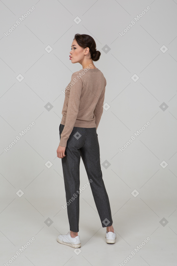 Three-quarter back view of a pouting lady in pullover and pants looking aside