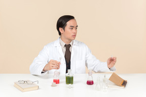 Ein asiatischer wissenschaftler in einem weißen kittel, der an einem chemischen experiment arbeitet