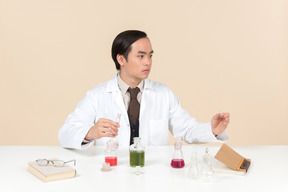 An asian scientist in a white coat working on a chemical experiment