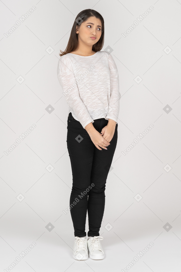 Disappointed young woman holding hands together and looking aside