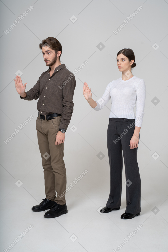 Vista de três quartos de um jovem casal com roupas de escritório estendendo a mão
